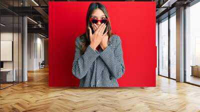 Young brunette woman wearing fashion and modern look shocked covering mouth with hands for mistake. secret concept. Wall mural