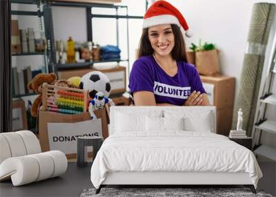 Young brunette woman wearing volunteer t shirt and christmas hat happy face smiling with crossed arms looking at the camera. positive person. Wall mural