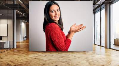 Young brunette woman with blue eyes wearing casual sweater over isolated white background pointing aside with hands open palms showing copy space, presenting advertisement smiling excited happy Wall mural