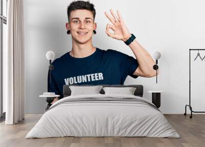 Young caucasian boy with ears dilation wearing volunteer t shirt smiling positive doing ok sign with hand and fingers. successful expression. Wall mural