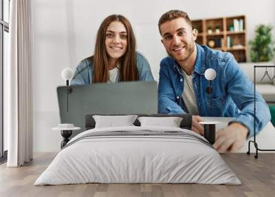 Young caucasian couple smiling happy using laptop at home. Wall mural