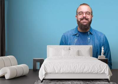 Young caucasian hipster man wearing glasses over isolated background with a happy and cool smile on face. Lucky person. Wall mural