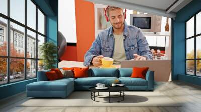 Young caucasian man drinking coffee listening to music dancing at dinning room Wall mural