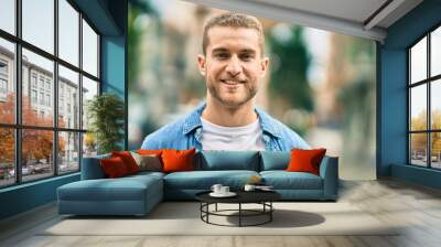 Young caucasian man smiling happy standing at the city. Wall mural