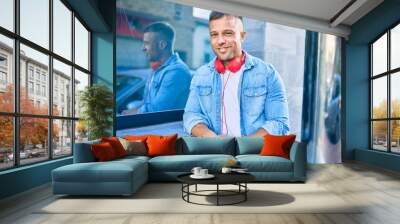 Young caucasian man smiling happy using headphones at the city. Wall mural