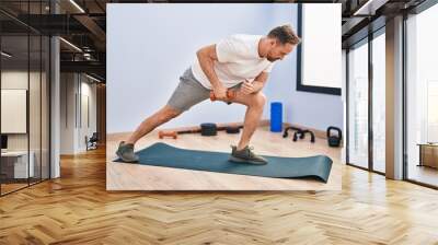 Young caucasian man using dumbbell training at sport center Wall mural