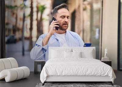 Young caucasian man using smartphone and credit card at street Wall mural