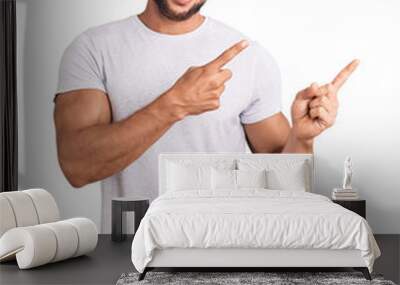 Young caucasian man wearing casual white tshirt smiling and looking at the camera pointing with two hands and fingers to the side. Wall mural