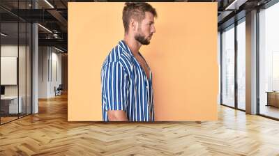 Young caucasian man wearing summer style looking to side, relax profile pose with natural face with confident smile. Wall mural