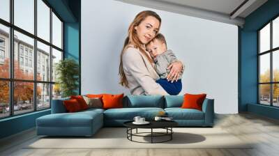 Young caucasian woman holding and hugging her son with love. Family of two bonding together. Mother holding infant toddler Wall mural