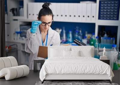 Young caucasian woman scientist reading book at laboratory Wall mural