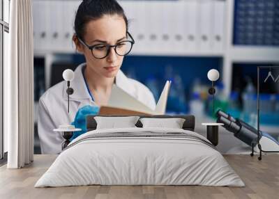 Young caucasian woman scientist reading book at laboratory Wall mural