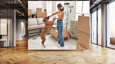 Young caucasian woman smiling confident listening to music and dancing with dog at home Wall mural