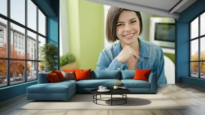 Young caucasian woman smiling confident sitting on table at home Wall mural