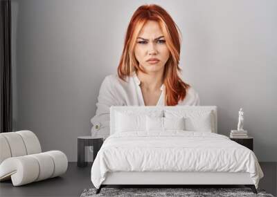 Young caucasian woman standing over isolated background skeptic and nervous, disapproving expression on face with crossed arms. negative person. Wall mural