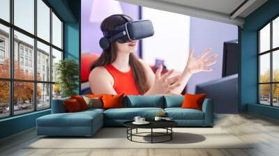 Young caucasian woman streamer playing video game using virtual reality glasses at gaming room Wall mural