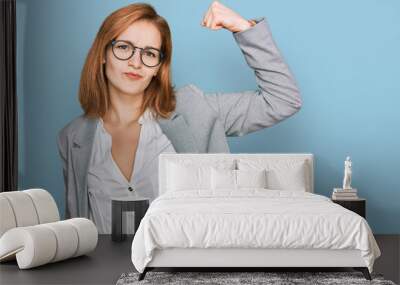 Young caucasian woman wearing business style and glasses strong person showing arm muscle, confident and proud of power Wall mural