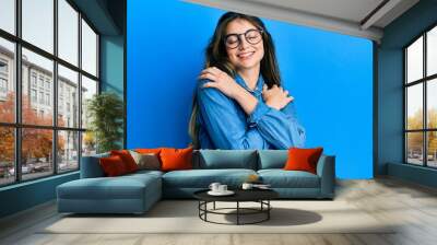 Young caucasian woman wearing casual clothes and glasses hugging oneself happy and positive, smiling confident. self love and self care Wall mural