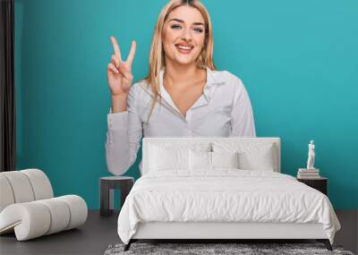 Young caucasian woman wearing casual clothes showing and pointing up with fingers number two while smiling confident and happy. Wall mural