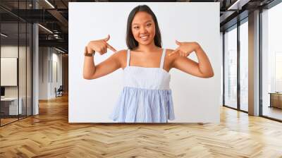 Young chinese woman wearing casual striped dress standing over isolated white background looking confident with smile on face, pointing oneself with fingers proud and happy. Wall mural