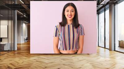 Young chinese woman wearing colorful striped t-shirt standing over isolated pink background happy face smiling with crossed arms looking at the camera. Positive person. Wall mural