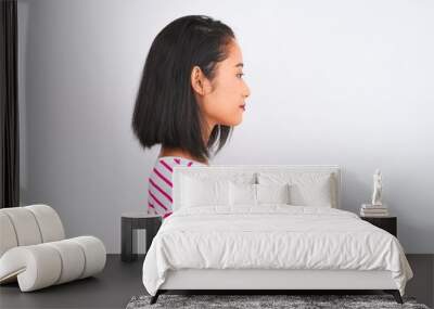 Young chinese woman wearing striped t-shirt standing over isolated white background looking to side, relax profile pose with natural face with confident smile. Wall mural