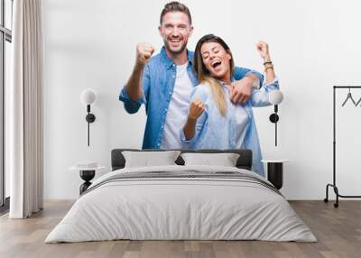 Young couple in love over isolated background very happy and excited doing winner gesture with arms raised, smiling and screaming for success. Celebration concept. Wall mural