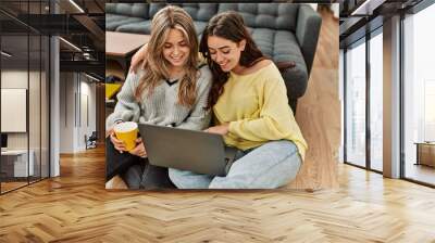 Young couple smiling happy using laptop drinking coffee at home. Wall mural