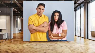 Young couple standing over isolated background shaking and freezing for winter cold with sad and shock expression on face Wall mural