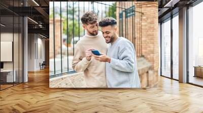 Young couple using smartphone standing together at street Wall mural