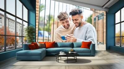 Young couple using smartphone standing together at street Wall mural