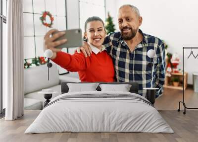 Young daughter and senior father together celebrating christmas at home taking selfie picture Wall mural