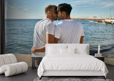 Young gay couple on back view kissing at the beach promenade. Wall mural