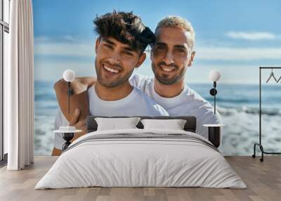 Young gay couple smiling happy hugging at the beach. Wall mural