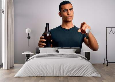 Young handsome african american man drinking bottle of beer over white background pointing with finger to the camera and to you, hand sign, positive and confident gesture from the front Wall mural