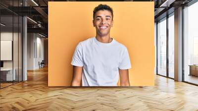 Young handsome african american man wearing casual white tshirt looking positive and happy standing and smiling with a confident smile showing teeth Wall mural