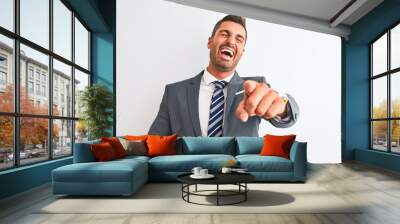 Young handsome business man wearing suit and tie over isolated background laughing at you, pointing finger to the camera with hand over body, shame expression Wall mural