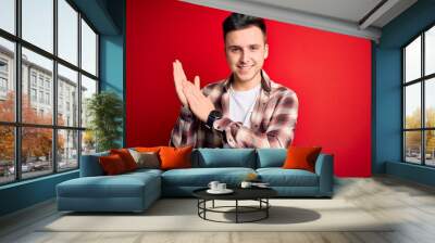 Young handsome caucasian man wearing casual modern shirt over red isolated background clapping and applauding happy and joyful, smiling proud hands together Wall mural