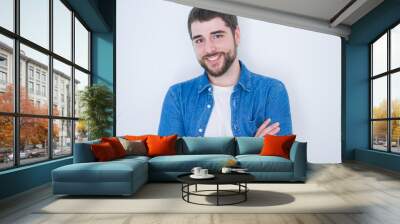 Young handsome hispanic man smiling at the camera with arms crossed looking happy and confident over isolated white background Wall mural