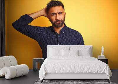 Young handsome indian businessman wearing shirt over isolated yellow background confuse and wonder about question. Uncertain with doubt, thinking with hand on head. Pensive concept. Wall mural