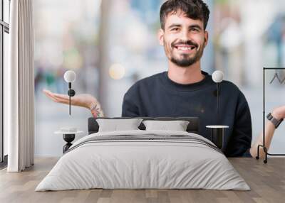 Young handsome man over isolated background Smiling showing both hands open palms, presenting and advertising comparison and balance Wall mural