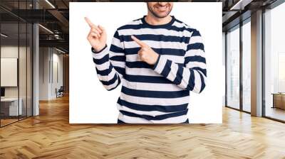 Young handsome man wearing burglar mask smiling and looking at the camera pointing with two hands and fingers to the side. Wall mural