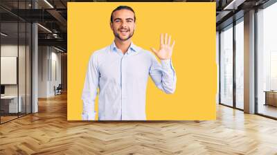 Young handsome man wearing business clothes showing and pointing up with fingers number five while smiling confident and happy. Wall mural