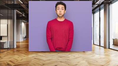 Young handsome man wearing casual clothes puffing cheeks with funny face. mouth inflated with air, crazy expression. Wall mural