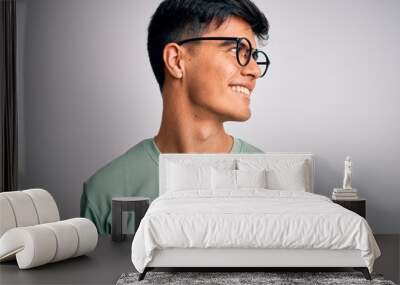 Young handsome man wearing casual t-shirt and glasses over isolated white background looking away to side with smile on face, natural expression. Laughing confident. Wall mural