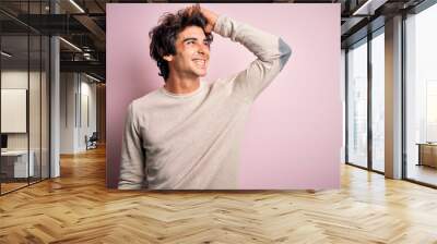 Young handsome man wearing casual t-shirt standing over isolated pink background smiling confident touching hair with hand up gesture, posing attractive and fashionable Wall mural