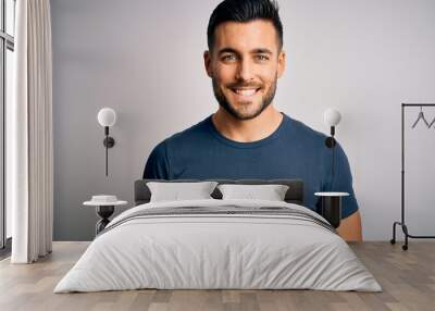 Young handsome man wearing casual t-shirt standing over isolated white background with a happy and cool smile on face. Lucky person. Wall mural