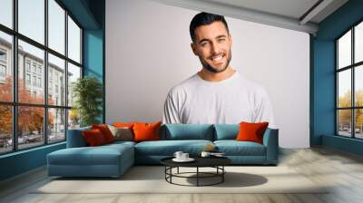 Young handsome man wearing casual t-shirt standing over isolated white background with a happy and cool smile on face. Lucky person. Wall mural