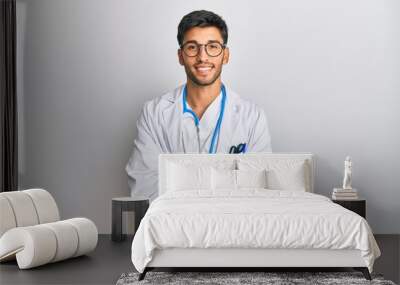 Young handsome man wearing doctor uniform and stethoscope happy face smiling with crossed arms looking at the camera. positive person. Wall mural