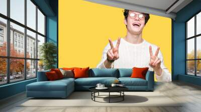 Young handsome man wearing glasses over isolated background smiling looking to the camera showing fingers doing victory sign. Number two. Wall mural